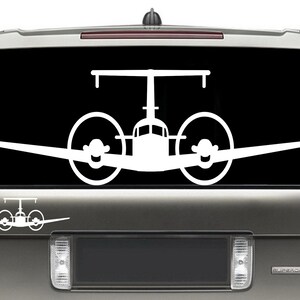 以下が含まれることがあります： 車の窓に貼るように設計された、プロペラ付きの双発機の白いビニールステッカーです。