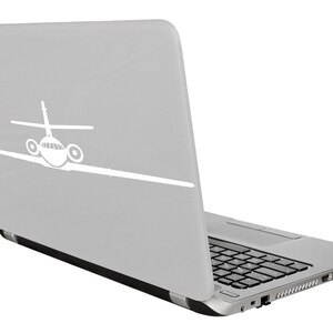 May include: A silver laptop with a white airplane silhouette on the lid. The laptop is closed and angled to the right.