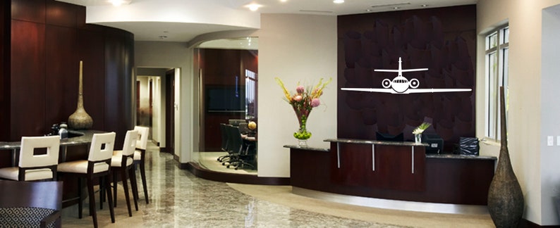 May include: A modern office lobby with a reception desk, a glass-walled conference room, and a large white airplane silhouette on the wall.