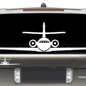 May include: A white silhouette of a private jet is displayed on the back window of a silver SUV. The jet is facing forward with the wings spread out.