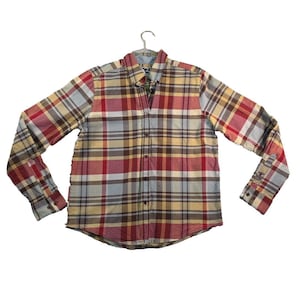 May include: A button-down plaid shirt in shades of red, yellow, blue, and brown. The long-sleeved shirt is hanging on a metal hanger. The shirt has a classic collar and buttoned cuffs.