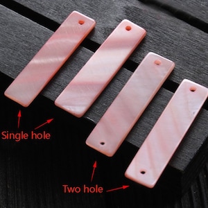 May include: Four pink rectangular shell pieces with holes for stringing. Two pieces have one hole, and two pieces have two holes.  "Single hole" and "Two hole" are labeled in red text.