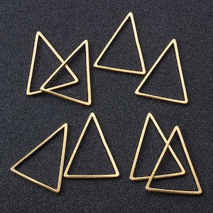May include: A set of eight gold-toned triangle-shaped metal hoops. The hoops are arranged in a random pattern on a black surface.