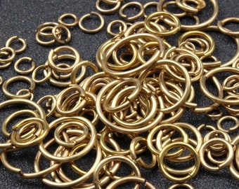 Puede incluir: Un montón grande de anillos de salto de metal de color dorado de varios tamaños. Los anillos están dispuestos en un patrón aleatorio y todos están hechos del mismo material.