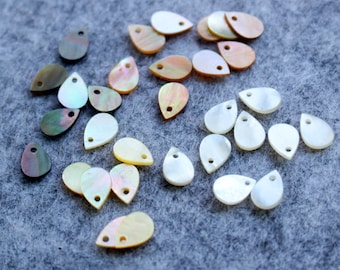May include: Assortment of teardrop-shaped shell beads in various colours, including white, cream, brown, and iridescent. The beads have a hole at the top for stringing.