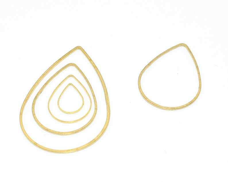 May include: Four gold teardrop-shaped wire hoops of varying sizes. The hoops are arranged in a nested pattern, with the largest hoop on the outside and the smallest hoop on the inside.