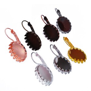 May include: Six pairs of silver, gold, copper, and bronze earring blanks with a scalloped edge. The earring blanks are oval shaped and have a clear glass insert.