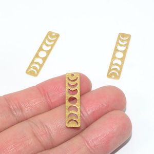 Può includere: Tre ciondoli in metallo dorato con un design a forma di luna crescente. Ogni ciondolo presenta otto diverse fasi lunari.