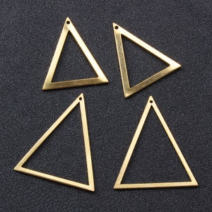May include: Four gold-coloured metal triangle shapes with a hole at the top. The triangles are hollow and have a smooth, shiny finish.