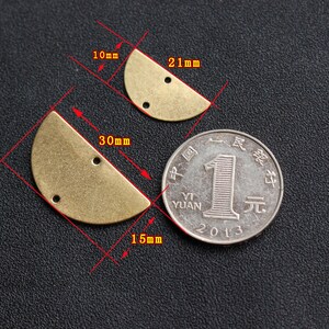 Puede incluir: Dos formas de medio c&iacute;rculo de lat&oacute;n con dos agujeros cada una. La forma m&aacute;s grande mide 30 mm de ancho y 15 mm de alto. La forma m&aacute;s peque&ntilde;a mide 21 mm de ancho y 10 mm de alto. Se incluye una moneda china yuan como referencia de tama&ntilde;o.