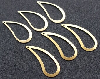 May include: Six gold-colored metal teardrop-shaped pendants with a hole at the top. The pendants are arranged in a semi-circle.
