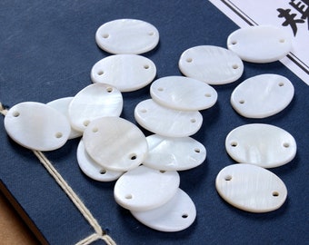 May include: A collection of white oval-shaped shell beads with two holes each. The beads are arranged in a random pattern on a blue surface.