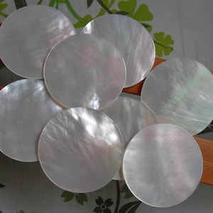 Pode incluir: Sete discos redondos de madrepérola branca iridescente.