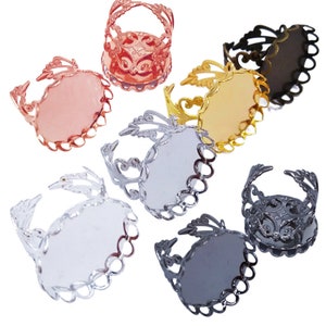 Op de afbeelding: Zes verschillende gekleurde metalen ringblanks met een filigraanontwerp. De blanks zijn ovaalvormig en hebben een vlak oppervlak om een cabochon aan toe te voegen.