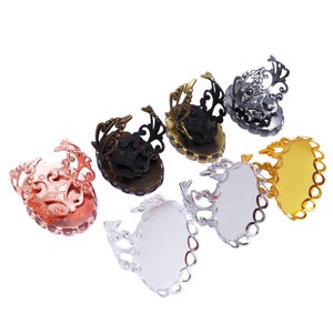 Op de afbeelding: Zes ovale ringblanken met sierlijke metalen frames in zilver, goud, zwart en rosé goud. De blanken zijn klaar om te worden gevuld met hars of andere materialen.