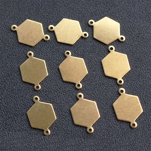 Op de afbeelding: Tien goudkleurige zeshoekige metalen connector charms met twee springringen aan elke charm. De charms zijn plat en hebben een geborstelde afwerking.