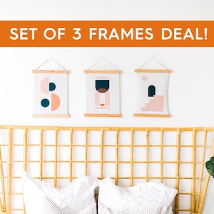 May include: Set of three framed abstract art prints with geometric shapes in shades of pink, blue, and white. The prints are hung on a white wall above a woven headboard.