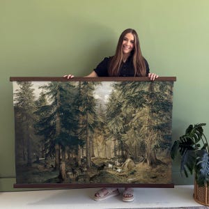 May include: A large, framed landscape print depicting a forest scene with tall trees, animals, and figures. The print has a dark brown wooden frame. The artwork features a muted color palette of greens, browns, and grays, creating a vintage aesthetic.