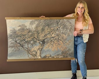 May include: A large, framed print of a detailed tree with a sprawling canopy. The artwork features muted tones of gray, brown, and blue, mounted on a wooden frame. The print depicts a landscape scene, suitable for wall decor.