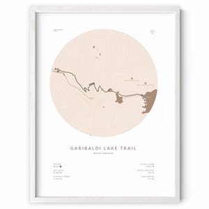 May include: A framed print featuring a map of the Garibaldi Lake Trail. The map is a light brown color, with a circular design and a white border. The trail's name and other details are printed in a minimalist font.