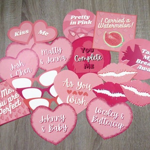 Puede incluir: Un conjunto de accesorios de cabina de fotos para el Día de San Valentín de color rosa y rojo con varias frases y diseños, incluidos corazones, labios, gafas de sol y texto como "Kiss Me", "To Me You Are Perfect", "You Complete Me" y "As You Wish".