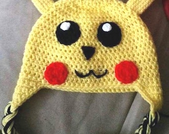 May include: A handmade yellow crochet hat resembling Pikachu, featuring black eyes, a black nose, red cheek circles, and pointed ears with black tips. The hat has a braided strap in yellow and black.