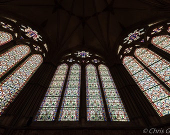 May include: A large stained glass window in a cathedral with intricate patterns in shades of red, blue, and green.
