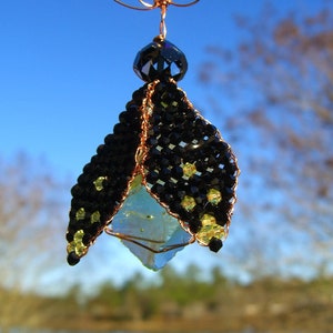 May include: A copper wire ornament with a blue and green crystal, black and yellow beads, and a copper wire loop at the top.