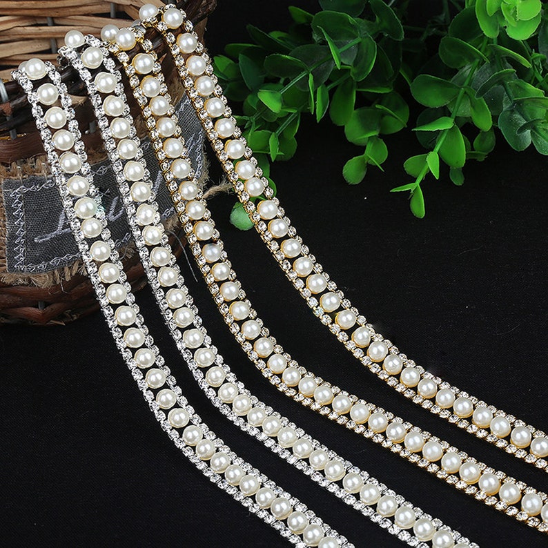 May include: Three strands of trim featuring a double row of faux pearls and a row of clear rhinestones.