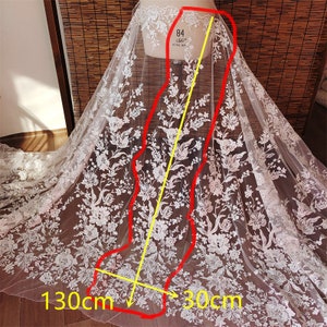 May include: White lace fabric with a floral pattern. The fabric is 130 cm wide and 30 cm long.