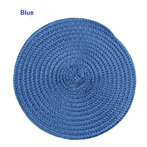 May include: A round, woven placemat in a vibrant blue color. The placemat is made of a tightly woven material, creating a textured surface. The word "Blue" is printed in white in the upper left corner. This item is suitable for kitchen and dining use.