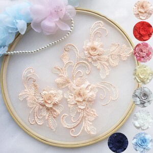 May include: A set of three delicate peach-coloured floral appliques with intricate lace detailing. The appliques feature a 3D flower design with a raised centre and delicate petals. The appliques are perfect for adding a touch of elegance to clothing, accessories, or home decor projects.