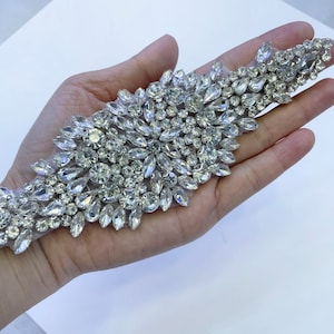 May include: A silver beaded trim with clear rhinestones, ideal for adding sparkle to clothing or crafts.