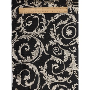 May include: Black fabric with a silver metallic floral pattern. The fabric has a textured, woven look.