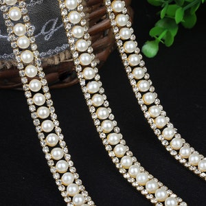 May include: Three strands of gold trim with alternating white pearls and clear rhinestones. The trim is perfect for adding a touch of elegance to any project.