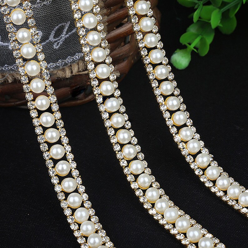 May include: Three strands of gold trim with alternating white pearls and clear rhinestones. The trim is perfect for adding a touch of elegance to any project.