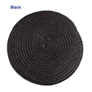 May include: A round, black woven placemat. The placemat is made of a tightly woven material, creating a textured surface. The word "Black" is printed in the upper left corner.