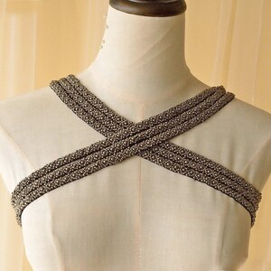 Könnte beinhalten: Ein silberner Perlen-Halter-Top mit Kreuzdesign.