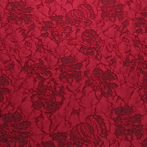 May include: Red fabric with a raised floral pattern. The fabric has a textured, embossed look.