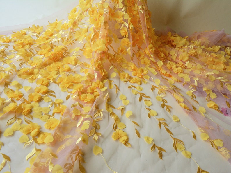 May include: Yellow floral lace fabric with 3D flowers and leaves. The fabric has a sheer, delicate texture and is perfect for adding a touch of elegance to any project.
