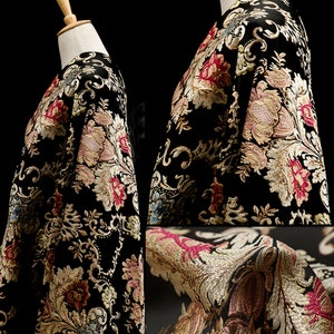 May include: A black jacket with a floral pattern in shades of gold, red, and pink. The fabric is textured and has a raised design.