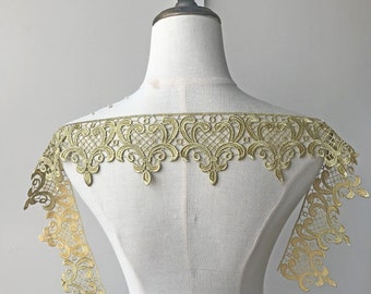 Puede incluir: Borde de encaje dorado con un delicado patrón floral. El encaje se muestra en un maniquí blanco.