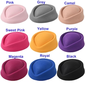 May include: A collection of nine pillbox hats in various colors, including pink, grey, camel, sweet pink, yellow, purple, magenta, royal blue, and black. Each hat has a rounded crown and a flat, circular brim. The hats are displayed in a grid.