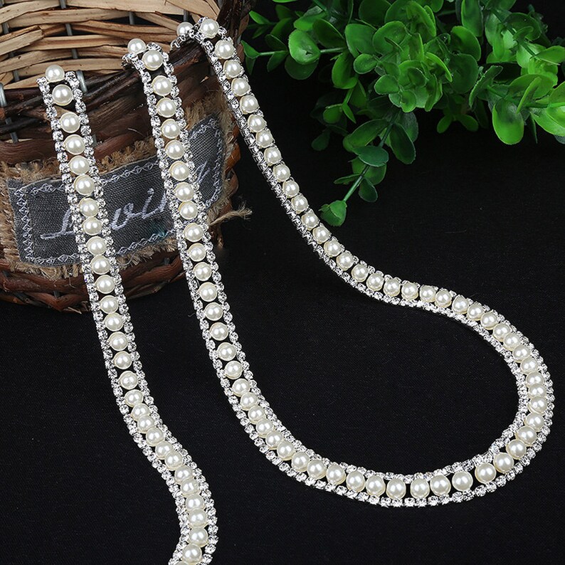 May include: A white pearl and rhinestone trim with a double row of pearls and a single row of rhinestones.