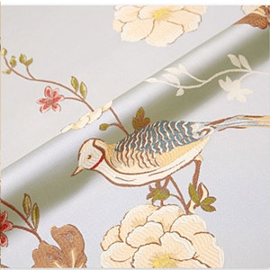 May include: A light blue fabric with a white and brown floral pattern and a bird with blue and brown feathers. The fabric has a subtle sheen and a soft texture.