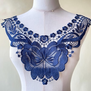 May include: Navy blue lace trim featuring a floral design. The lace is delicate and intricate, with a scalloped edge.