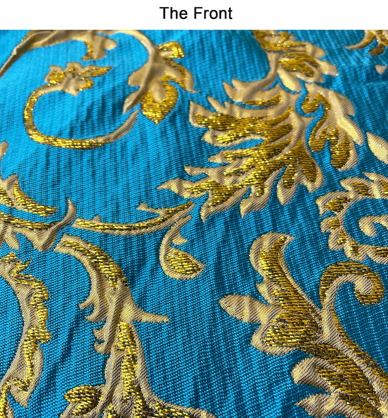 May include: Close-up of a teal fabric with a gold embroidered floral pattern. The fabric has a textured, woven look.