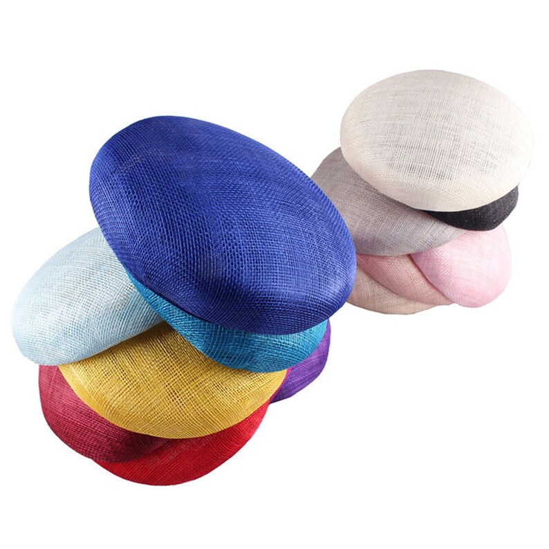 May include: A collection of oval-shaped hats in various colors, including blue, red, yellow, and pink. The hats are made of a woven material, and are stacked together. The hats are likely for formal occasions.