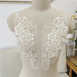 May include: Two white lace appliques with floral designs, perfect for adding a touch of elegance to wedding dresses, bridal gowns, or other special occasion garments.