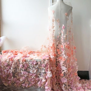 May include: Pink and peach floral lace fabric with 3D flowers. The fabric is sheer and delicate, with a soft, romantic feel.